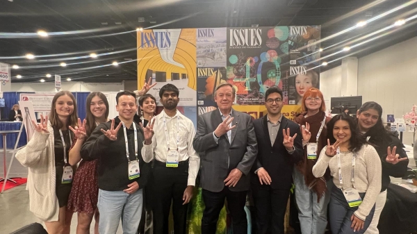 A group of students and Michael Crow holding up the "forks up" symbol at AAAS.